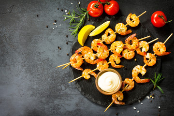 Grilled seafood. Delicious Grilled shrimps with spice, lemon and sauce served on a slate board. Seafood. Top view flat lay background.