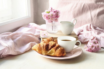 Spring still life scene. Cup of coffee, croissant pastry, old books and milk pitcher. Vintage...
