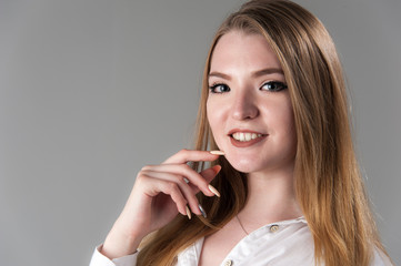 Portrait of a young attractive woman with blond hair on a neutral gray background.