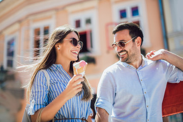 Happy couple having date and eating ice cream after shopping