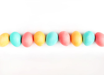 Fototapeta na wymiar Colorful Easter eggs lined on white background. Flat lay.