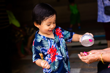  Young boy pouring water and flowers on the hands. older women and happy for the songkran festival Thailand