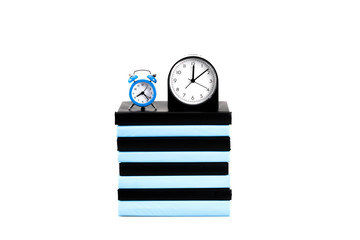 Clocks and stack of books isolated on white