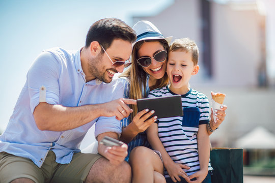 Smiling parents and little boy with tablet pc and credit card outdoor