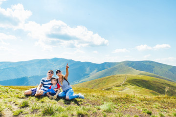 young family on the top of the peak. woman pointing somewhere. travel concept