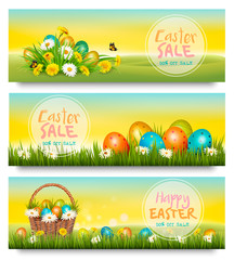 Three Easter Sale banners. Colorful eggs in green grass and spring flowers. Vector.