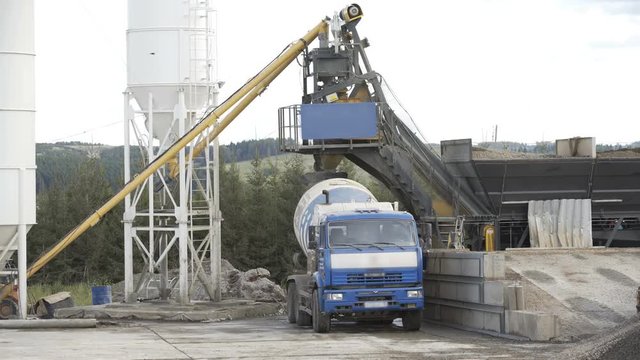 Loading mixer truck on concrete-asphalt factory. Concept of cisterns, pipes, metal structures, concrete production
