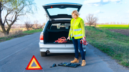 Car problems, red warning triangle! Young woman with warning triangle on street . Girl repairing car