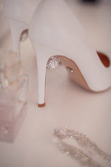 white shoes with high heels stand next to toilet water and earrings with crystals.