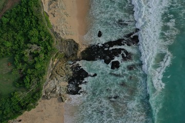 Fototapeta na wymiar Aerial view of Uluwatu Temple and wave breaking on rocks on the beach near cliff. Bali, Indonesia.