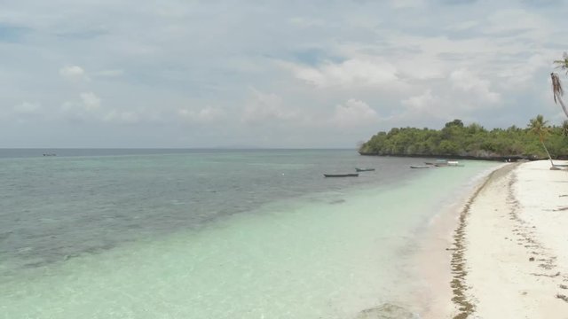 Aerial: Flying over tropical beach turquoise water coral reef , Tomia island Wakatobi National Park Indonesia Maldives Polynesia white sand beach. Native cinelike D-log color profile