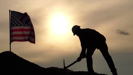 Concept Labor Day: Labor man standing holding a pickaxe with the United States flag footage slow motion