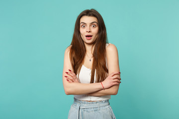 Portrait of excited young woman in light casual clothes looking camera holding hands crossed isolated on blue turquoise wall background. People sincere emotions, lifestyle concept. Mock up copy space.