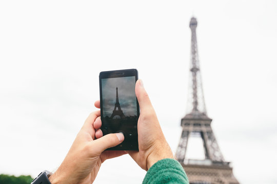 Hands Caucasian male tourist blogger makes the most important sights Paris France Eiffel Tower photo using smartphone