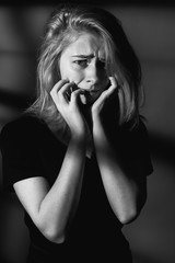 Scared young woman in shadows. Black and white