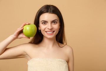 Close up brunette half naked woman 20s with perfect skin, nude make up hold apple isolated on beige pastel wall background, studio portrait. Healthcare cosmetic procedures concept. Mock up copy space.