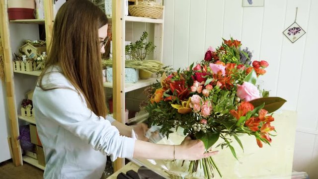 Female florist in flower shop. Woman making a beautiful and stylish bouquet of fresh flowers in floral design studio. 4K