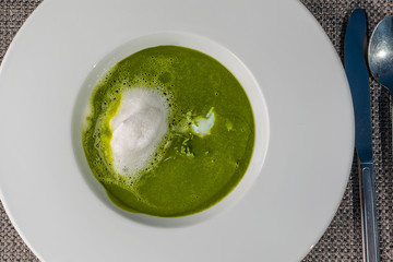 healthy spinach soup served with egg on white plate, spring soup full of vitamins, product photography for restaurant