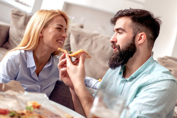 Young couple eating pizza at home