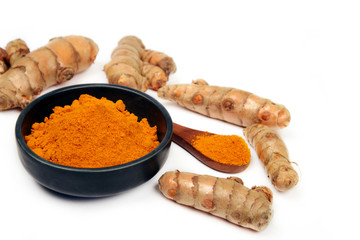 Organic healthy Turmeric powder in a bowl with Turmeric roots on white background
