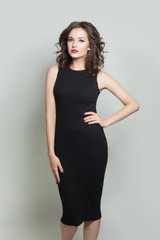 Pretty model woman in black dress posing on white background