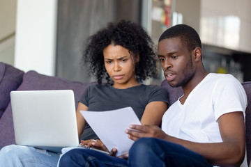 Shocked African American couple receiving bad news, reading letter