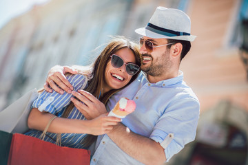 Obraz premium Happy couple having date and eating ice cream after shopping