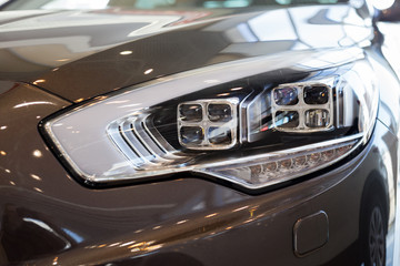 New modern car with elegant quadrate head lamps. Front view.
