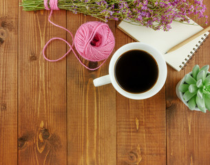 Flat lay,top view grey wooden desk with stationery including notebook and pencil with a cup of coffee,flowers and copy space