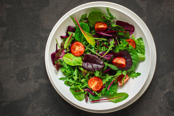 salad with tomato, lettuce, arugula, spinach and other leaves. food background. top