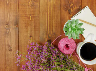Flat lay,top view grey wooden desk with stationery including notebook and pencil with a cup of coffee,flowers and copy space