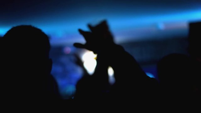 Silhouette waving their hands at a rave
