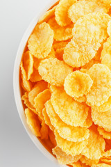 White cup with golden corn flakes isolated on white background. View from above. Delicious and healthy breakfast