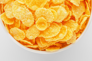 White cup with golden corn flakes isolated on white background. View from above. Delicious and healthy breakfast