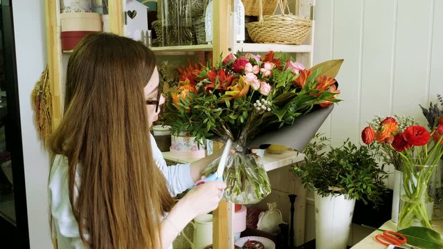 Female florist in flower shop. Woman making a beautiful and stylish bouquet of fresh flowers in floral design studio. 4K