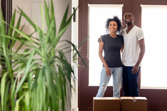 Happy African American couple standing in hall of new house