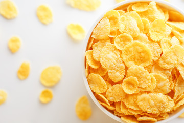 White cup with golden corn flakes, isolated on white background. Hopya crumbled around the cup. View from above