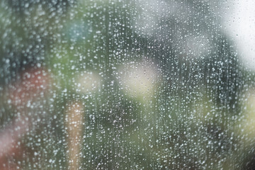 Glass window with raindrops. Overcast day and blurred cityscape outside. Symbol of sadness, depression, sorrow. Abstract texture background with copy space for text and design. Realistic image.