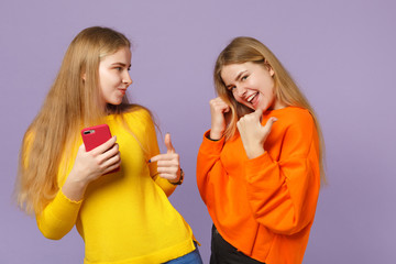 Two cheerful young blonde twins sisters girls in vivid clothes p
