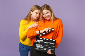 Two smiling young blonde twins sisters girls in colorful clothes