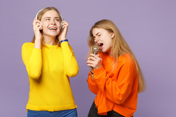 Two cheerful blonde twins sisters girls in vivid clothes listen