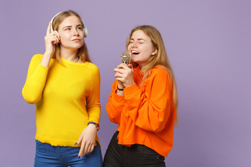 Two cheerful blonde twins sisters girls in vivid clothes listen