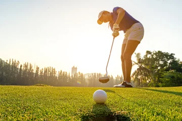 Tuinposter Sport Healthy. Golfer asian sporty woman focus putting golf ball on the green golf on sun set evening time.  Healthy and Lifestyle Concept © freebird7977