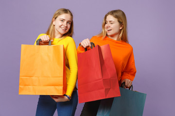 Two joyful young blonde twins sisters girls in vivid clothes hol
