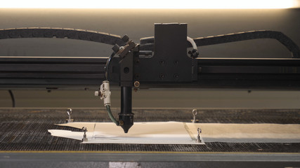 In an industrial garment factory, a special Laser Cutting Fabric cuts out certain textile pieces. Concept of: Laser machine, Crosses, Work in a factory, Automatic cutting.
