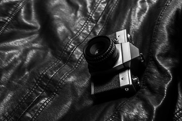 Vintage, antique and old analog camera on leather jacket