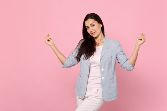 Portrait of smiling beautiful young woman in striped jacket rubbing, snapping fingers isolated on pink pastel wall background in studio. People sincere emotions, lifestyle concept. Mock up copy space.