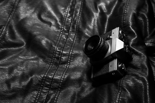 Vintage, antique and old analog camera on leather jacket