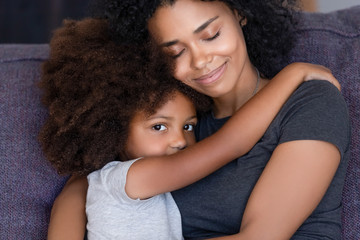Head shot portrait African American mother embracing daughter