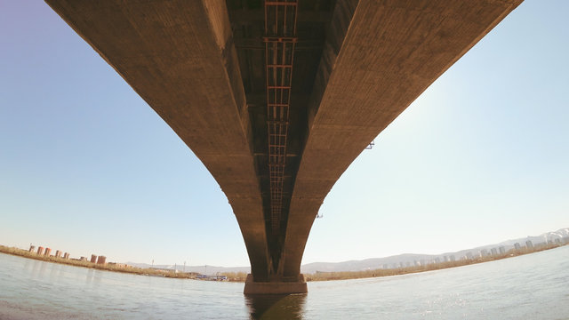 The arch of the communal bridge in the city of Krasnoyarsk (Internal arch - intrados). Bridge over the big Yenisei River. Sunny, a lot of concrete hanging over the waters of the river.